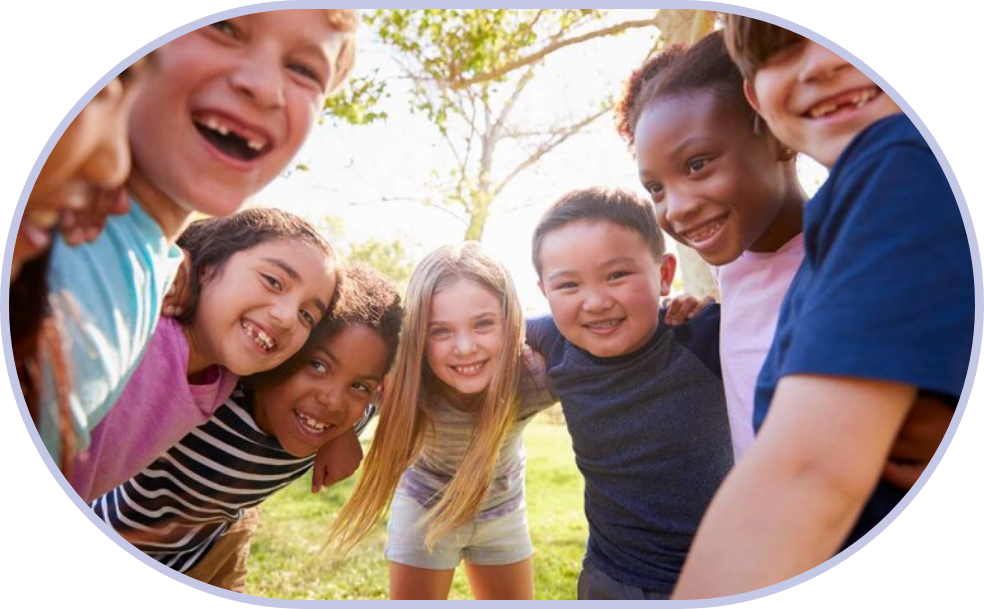 A group of smiling children wrap armms around each other's shoulders to create a circle